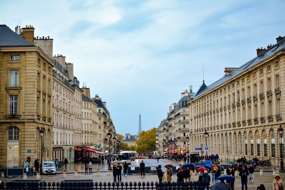 Wide view across Paris streets and rooftops with the Eiffel Tower in the distance