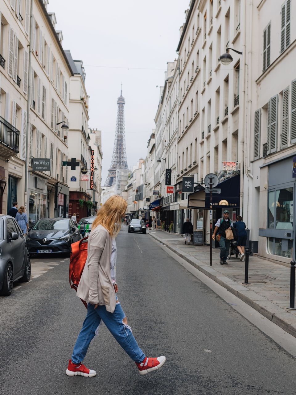 Person crossing a Paris street with the Eiffel Tower in the distance